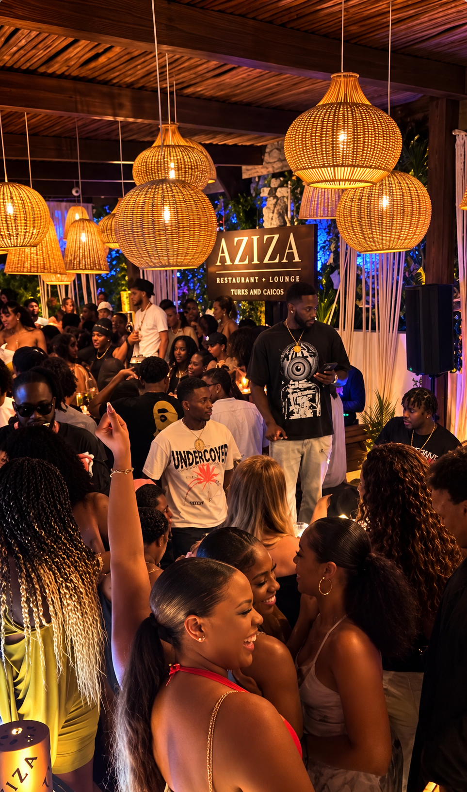 Aziza Restaurant + Lounge at night with woven pendant lanterns and a lively crowd